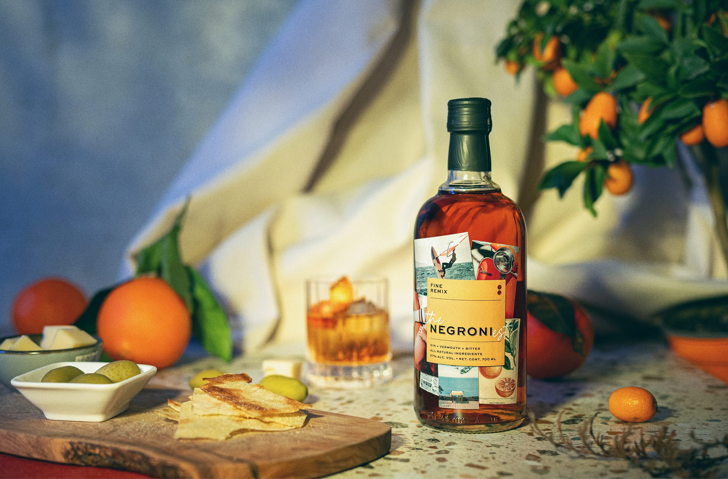 Boca Negronija i puna čaša, s narančama, maslinama, sirom i krekerima